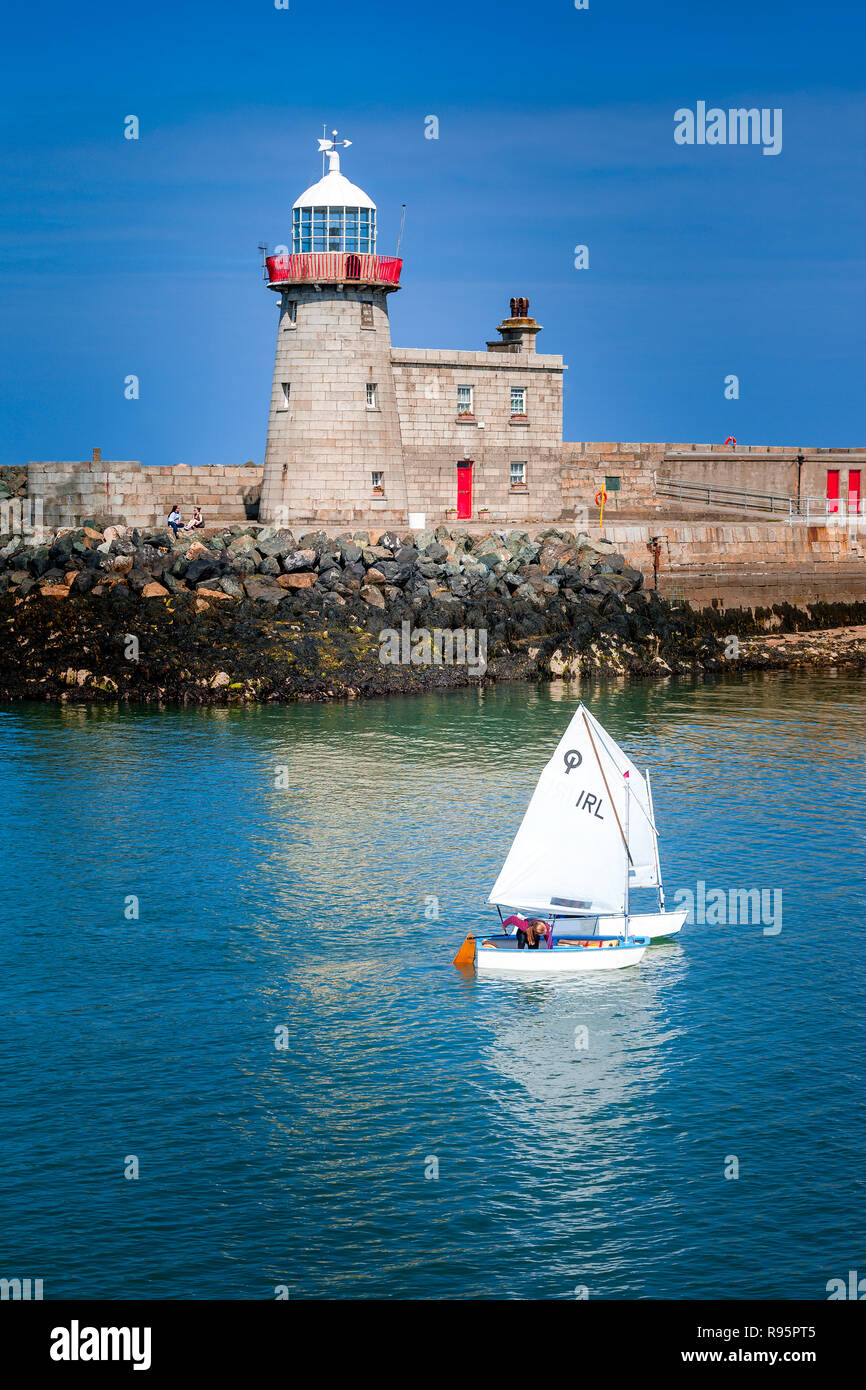 Un bianco di crociera in barca a vela in prossimità di un faro su acqua blu, Malahide, Dublino, Irlanda Foto Stock