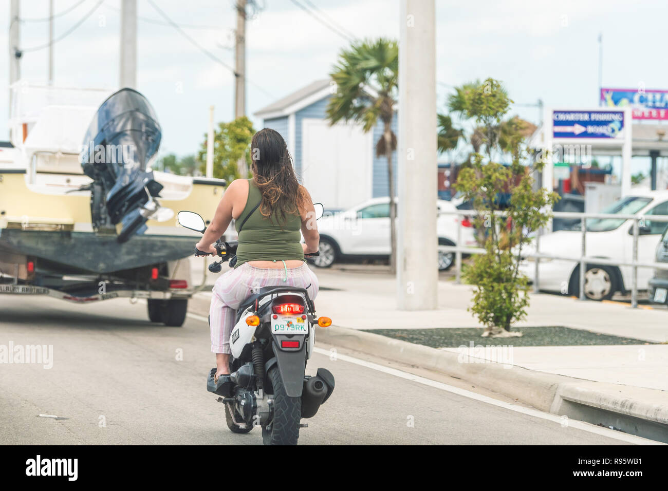 Key West, Stati Uniti d'America - 1 Maggio 2018: Overseas Highway Road, US1, traffico di automobili in piedi, arrestato, indietro alle spalle della donna seduta, equitazione motocicletta, scooter Foto Stock