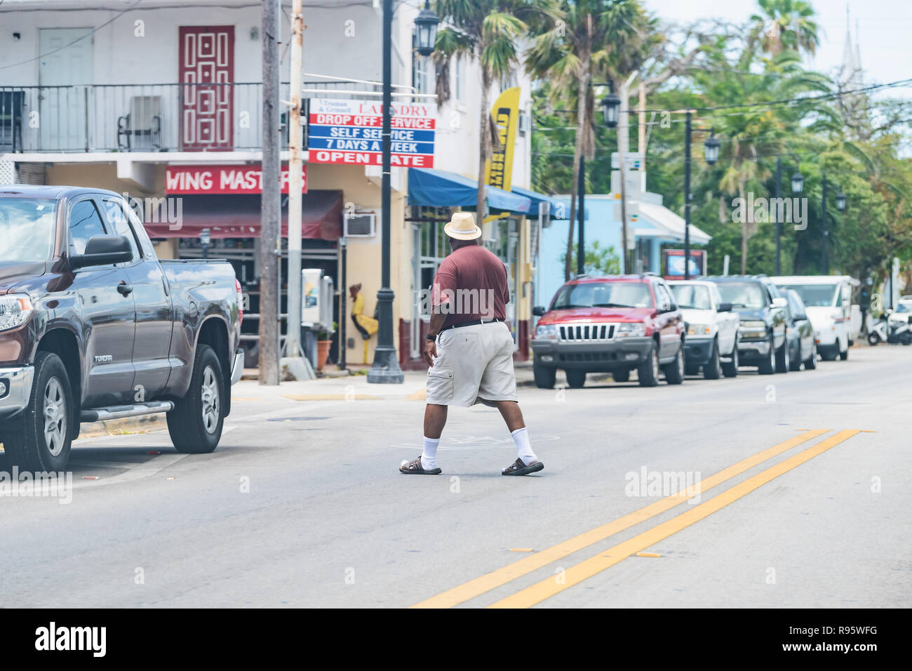 Key West, Stati Uniti d'America - 1 Maggio 2018: Truman Avenue in Florida keys city, la veduta urbana sulla strada, corso auto, servizio lavanderia Negozio con African American uomo crossing, j Foto Stock