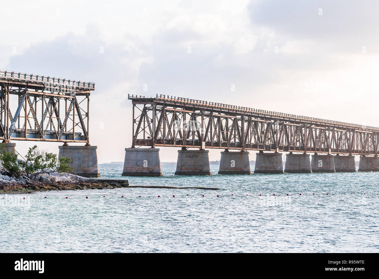 Vecchio arrugginito, ruggine, rusty derelitti Bahia Honda rail road bridge in stato parco con vista sulla riva, costa, albero, nuvole, nuvoloso cielo blu al tramonto, crepuscolo, Foto Stock