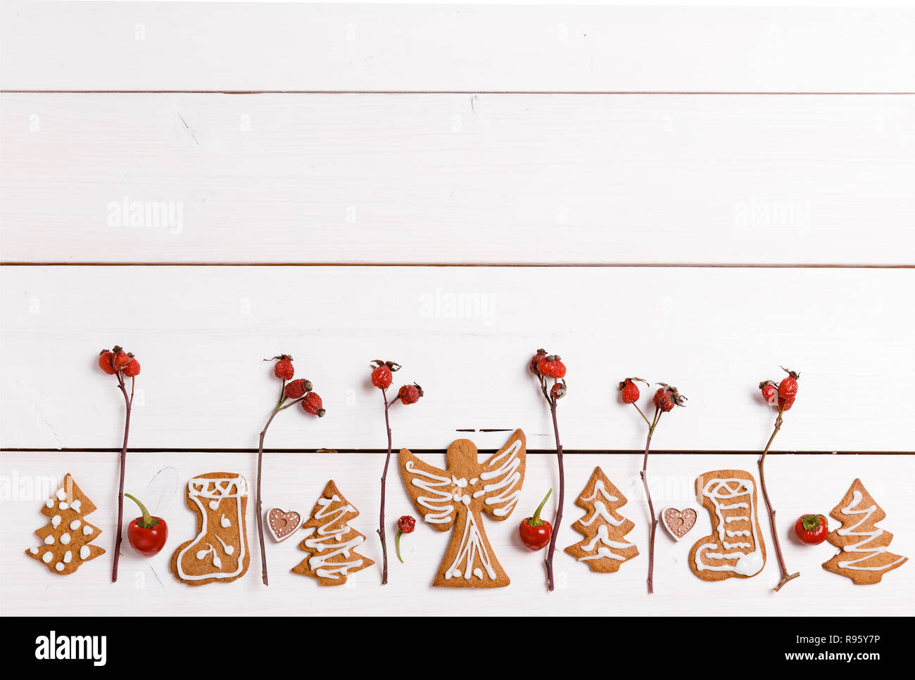 Natale in casa gingerbread cookie e Rosso di bacche di rosa canina, bianco su un tavolo di legno. Banner di natale. T Foto Stock