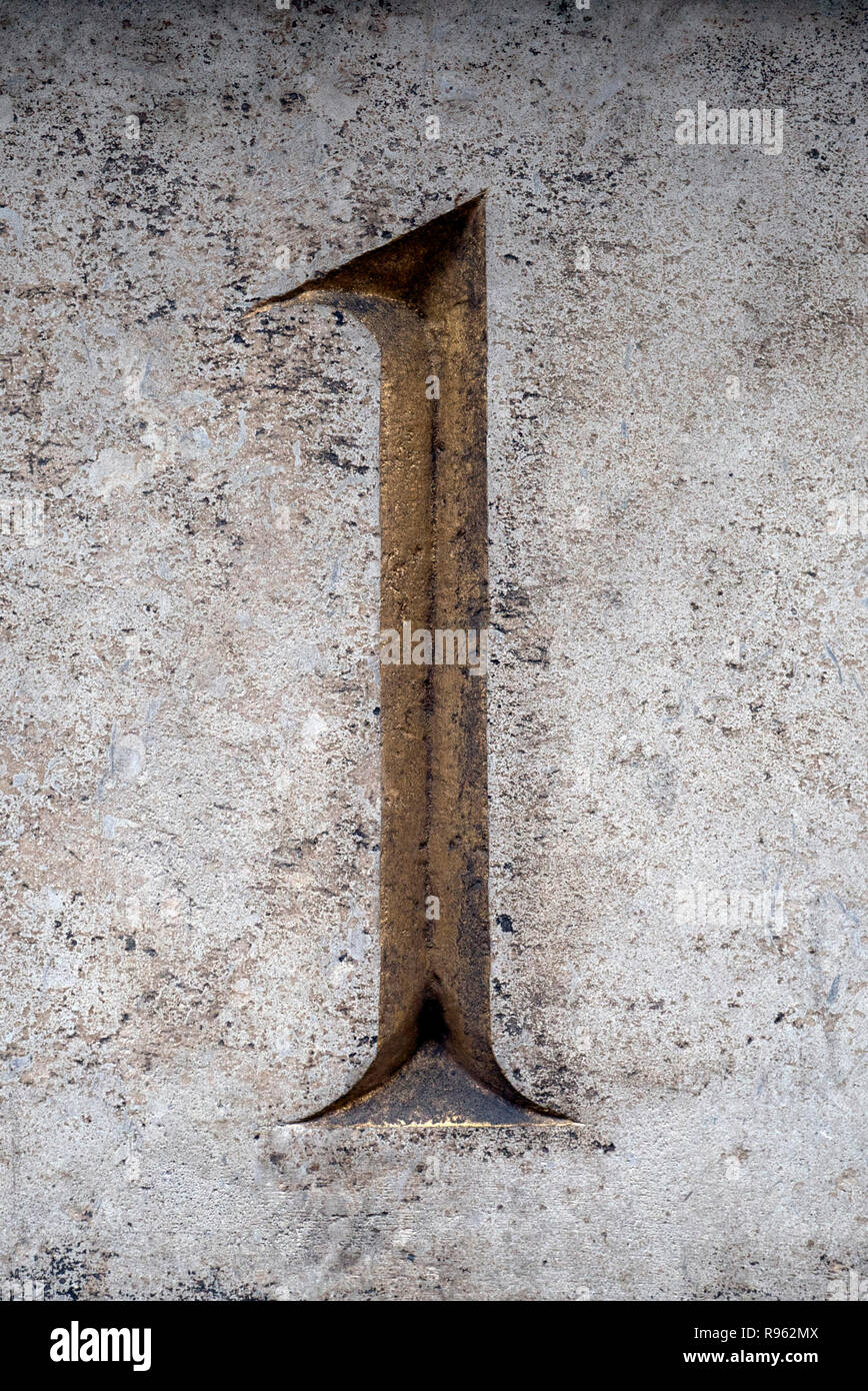 Un oro numero uno numero porta scolpito in una parete di pietra Foto Stock