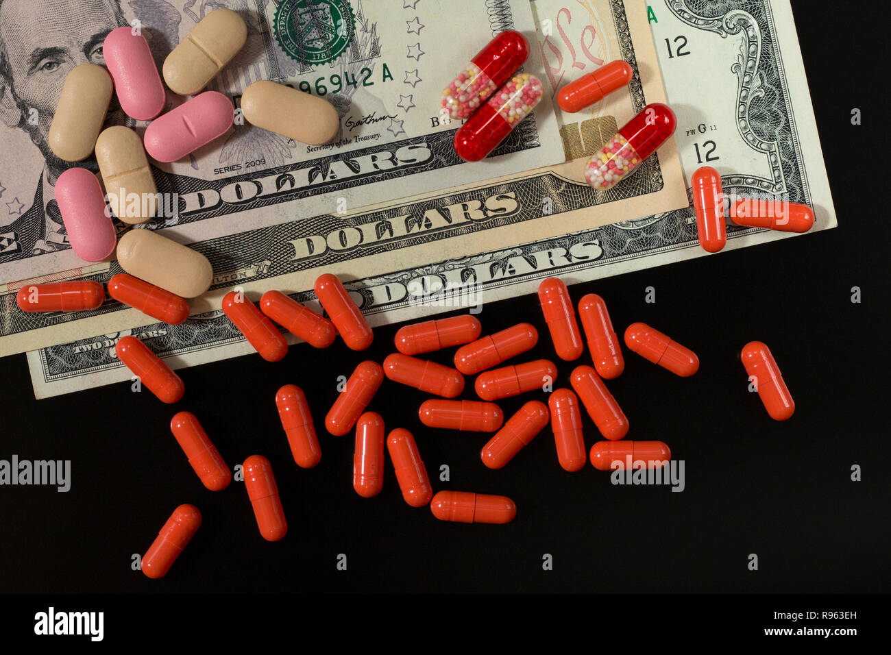 Rosso, beige, rosa pillole sulle fatture del dollaro. Spese mediche. Farmacia Azienda. Foto Stock