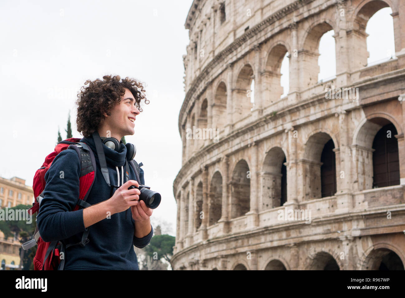 Bel giovane uomo turistica con una fotocamera zaino e scattare foto del Colosseo a Roma, Italia. Giovani turisti scattare foto del Colosseo Foto Stock
