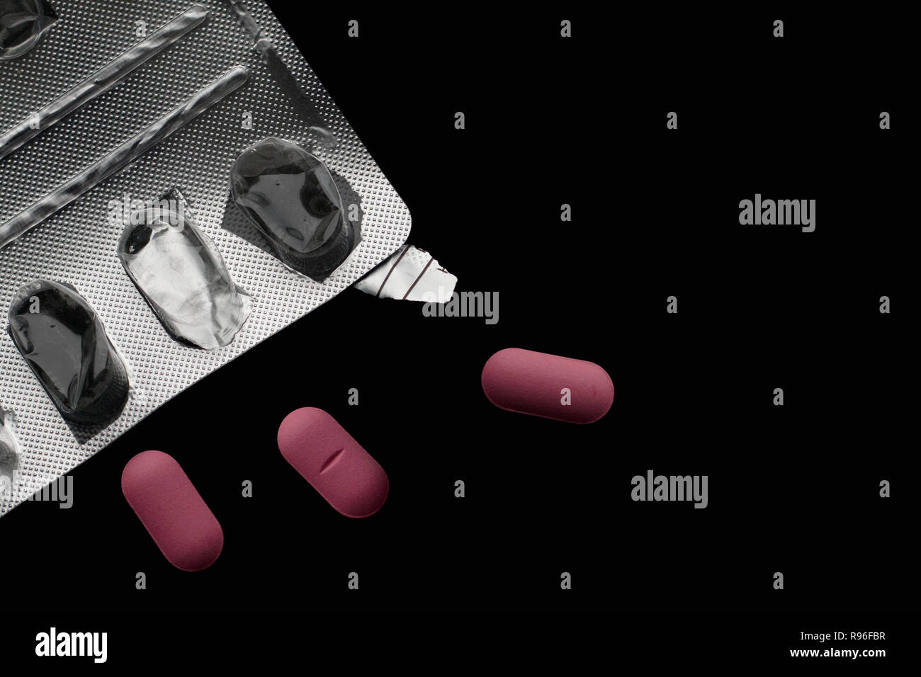 Svuotare blister e tre pillole rosa su sfondo nero con spazio di copia Foto Stock