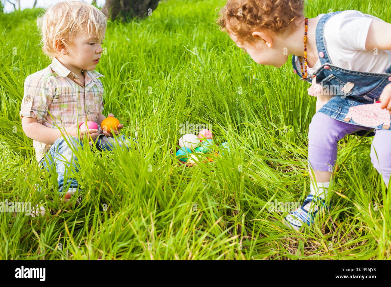 Due graziosi toddlers trovato uova colorate durante le festività di Pasqua Caccia Foto Stock