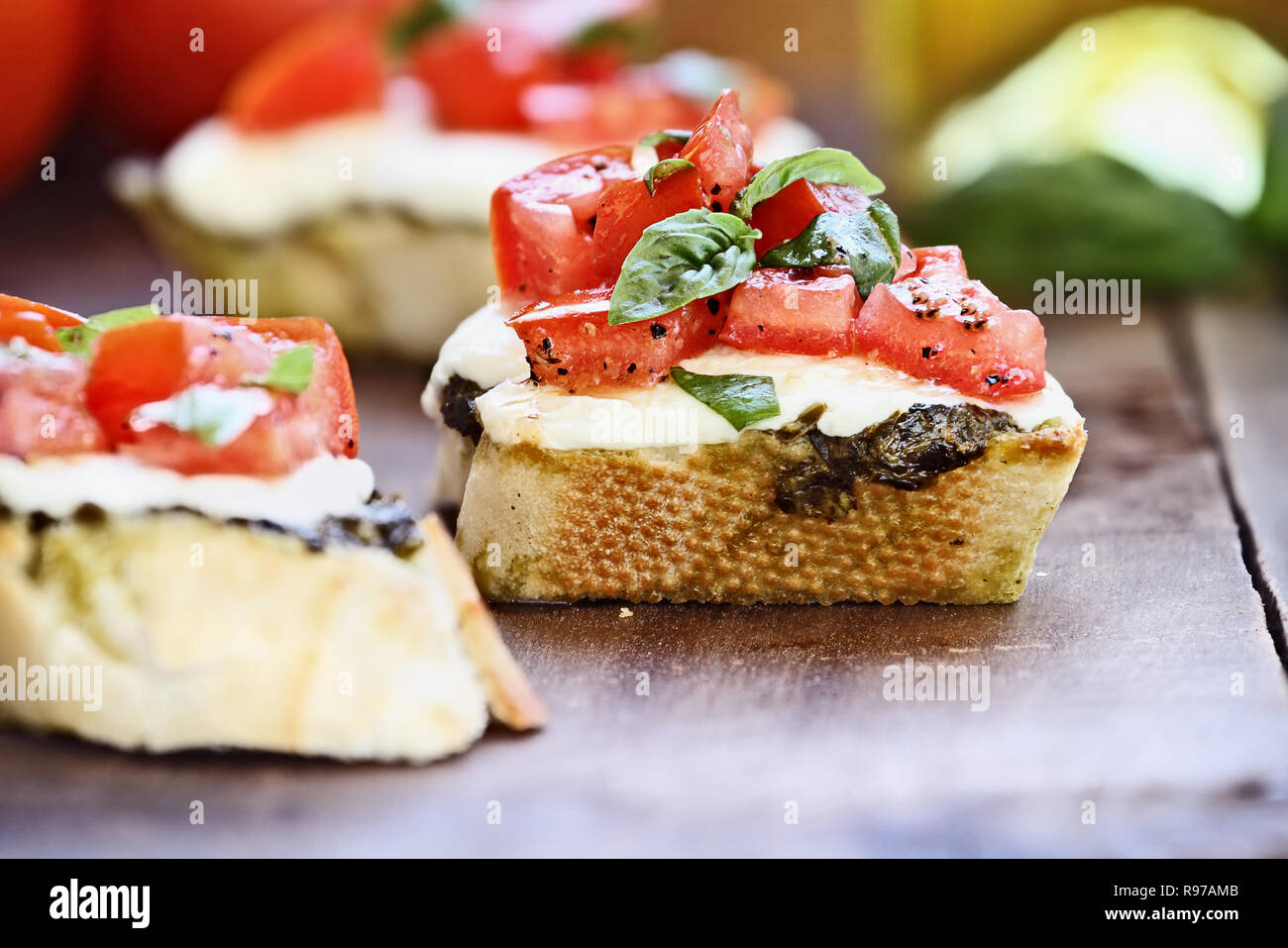 Antipasti Bruschetta con pomodoro, mozzarella e pesto. Sfocare lo sfondo con il fuoco selettivo sul centro sandwich. Foto Stock