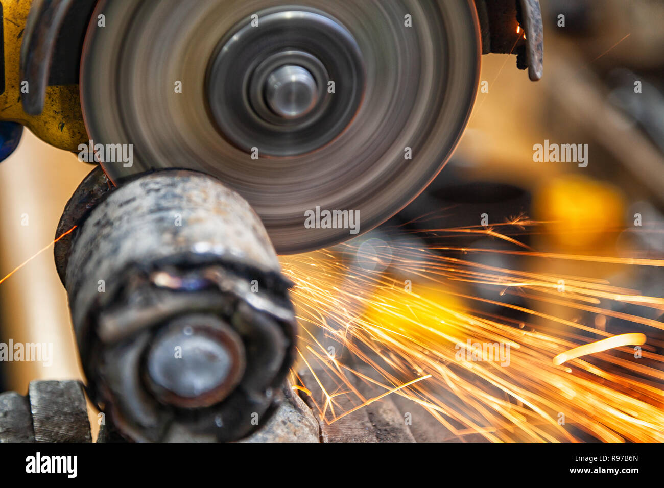 Un close-up di un meccanico utilizzando un metallo smerigliatrice per tagliare un auto blocco silenzioso in un negozio di riparazioni auto, luminoso lampeggia battenti in direzioni diverse. Wo Foto Stock