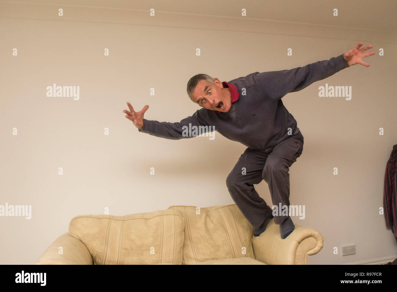 Nonno, uomo anziano, che agisce da stolto, saltando su mobili, Foto Stock