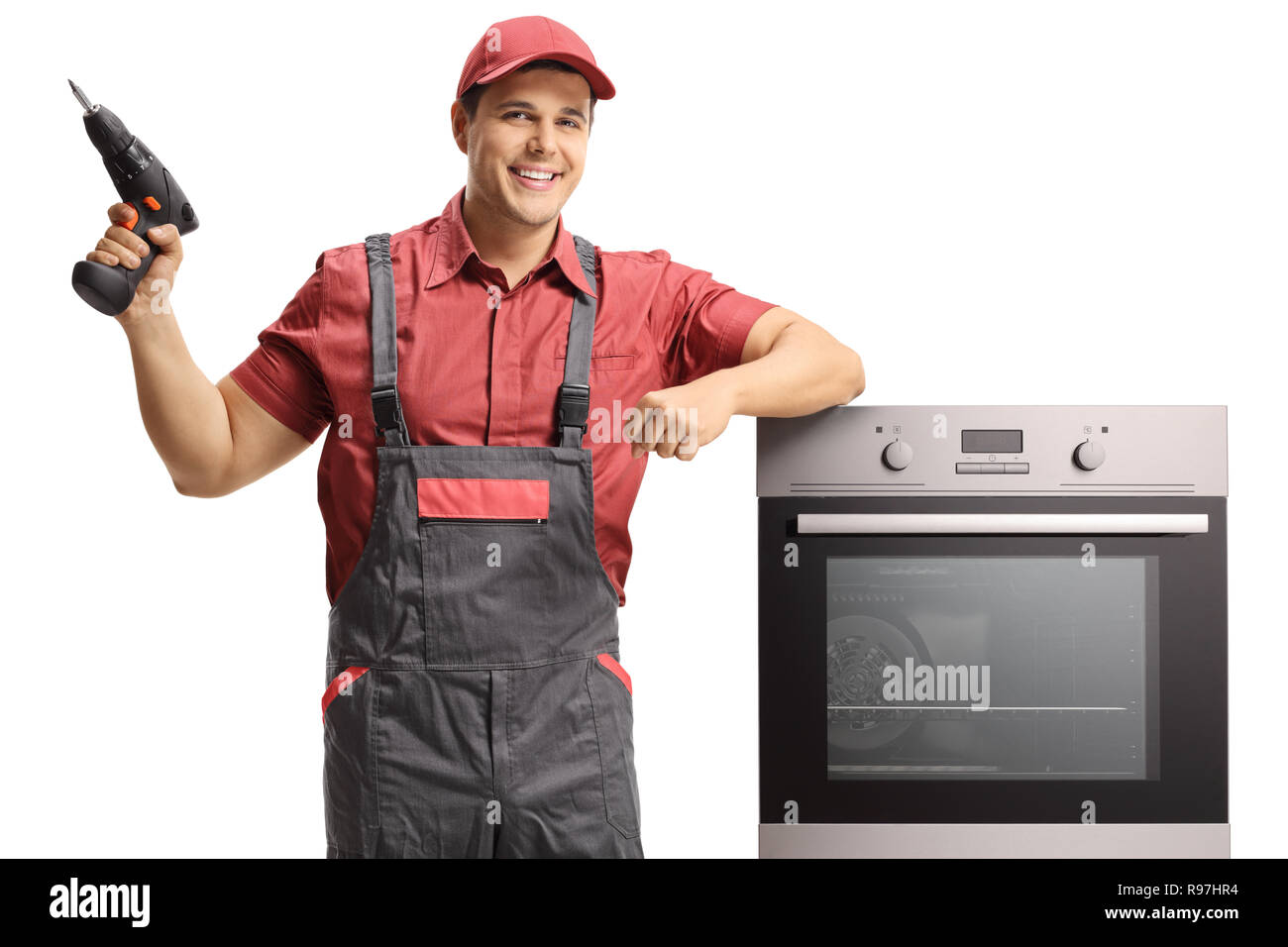 Repairman con un trapano elettrico in piedi accanto ad un forno isolato su sfondo bianco Foto Stock