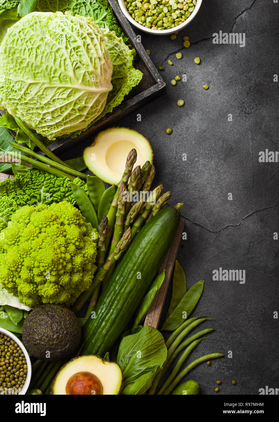 Assortiti nei toni del verde materie verdure organiche su sfondo scuro. Avocado, cavoli broccoli, cavolfiori e cetriolo con fagioli rifilati. Foto Stock