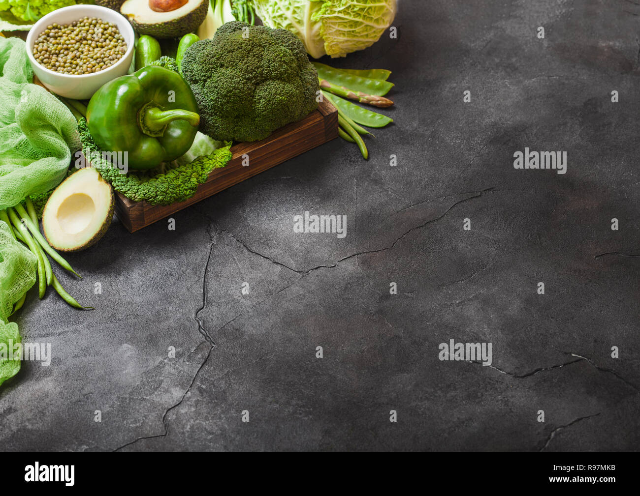 Assortiti nei toni del verde materie verdure organiche su sfondo scuro. Avocado, cavoli broccoli, cavolfiori e cetriolo con fagioli rifilati. Foto Stock