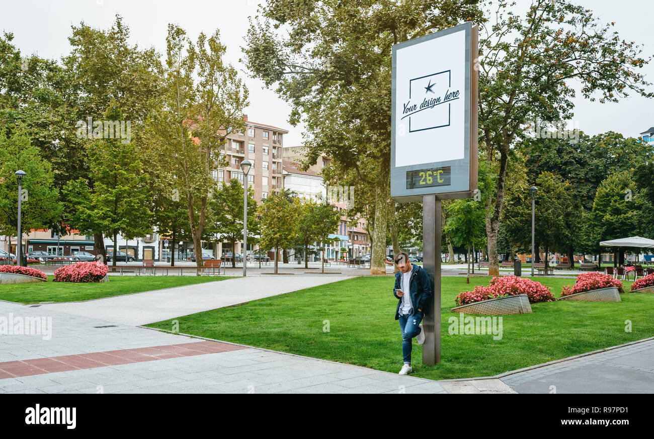 Uomo che guarda mobile appoggiato su un tabellone personalizzabile Foto Stock
