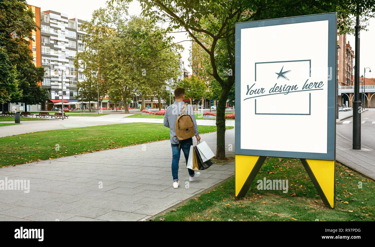 Uomo che cammina accanto a una soluzione personalizzabile poster pubblicitario Foto Stock