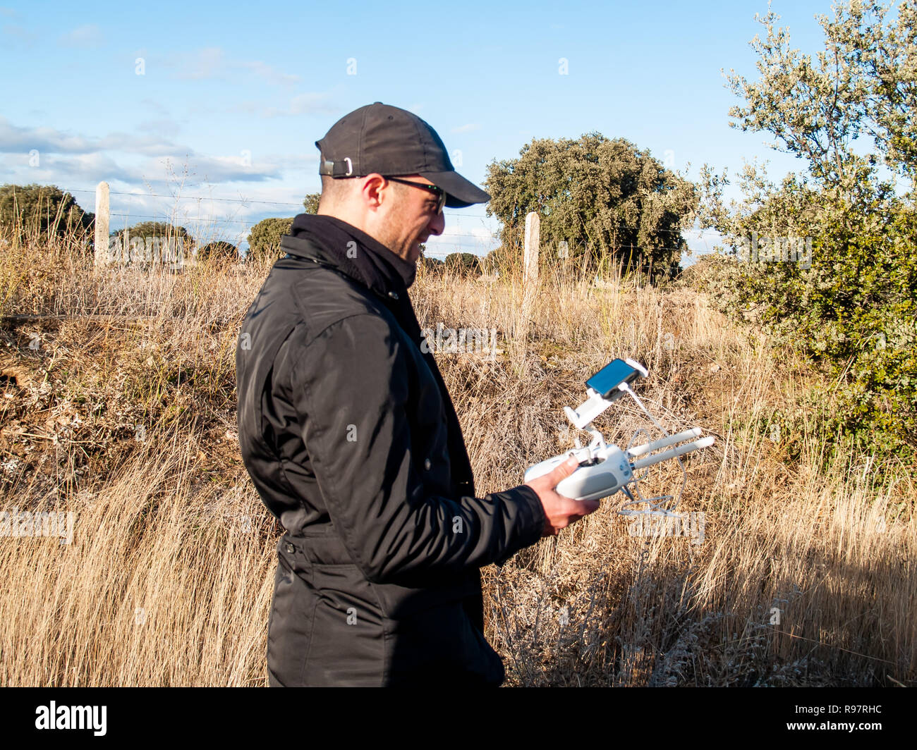 Un drone di pilotaggio pilota con il telecomando con lo smartphone nelle sue mani nella foresta Foto Stock