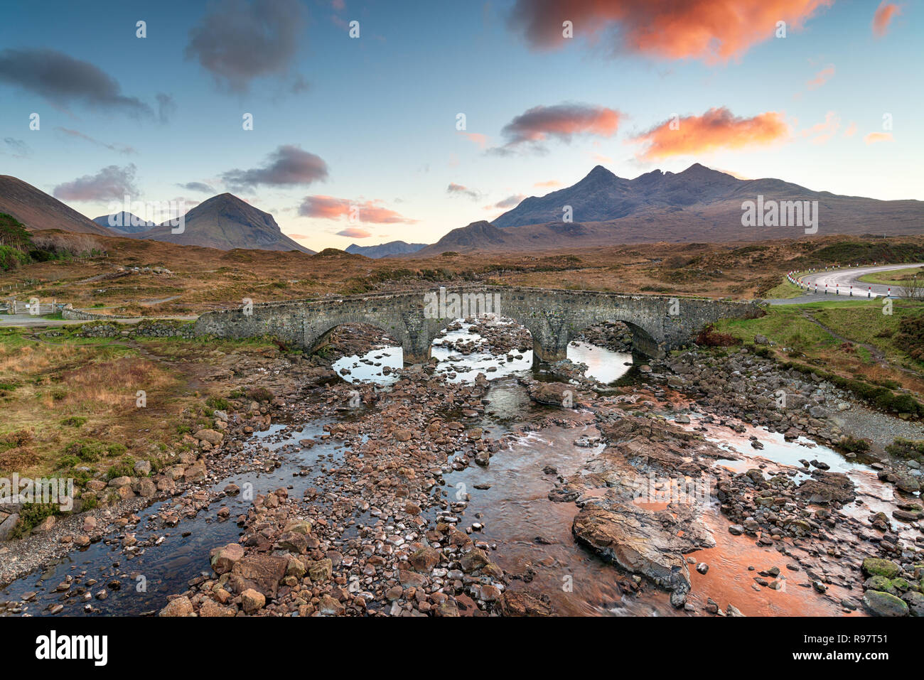 Il tramonto del vecchio ponte di Sligachan sull'Isola di Skye in Scozia con le montagne Cuillin in background Foto Stock