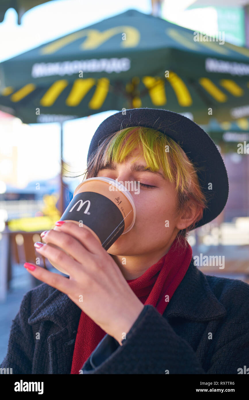 KALININGRAD, RUSSIA - circa aprile, 2018: donna caucasica beve caffè al ristorante McDonald's nella Regione di Kaliningrad. Foto Stock