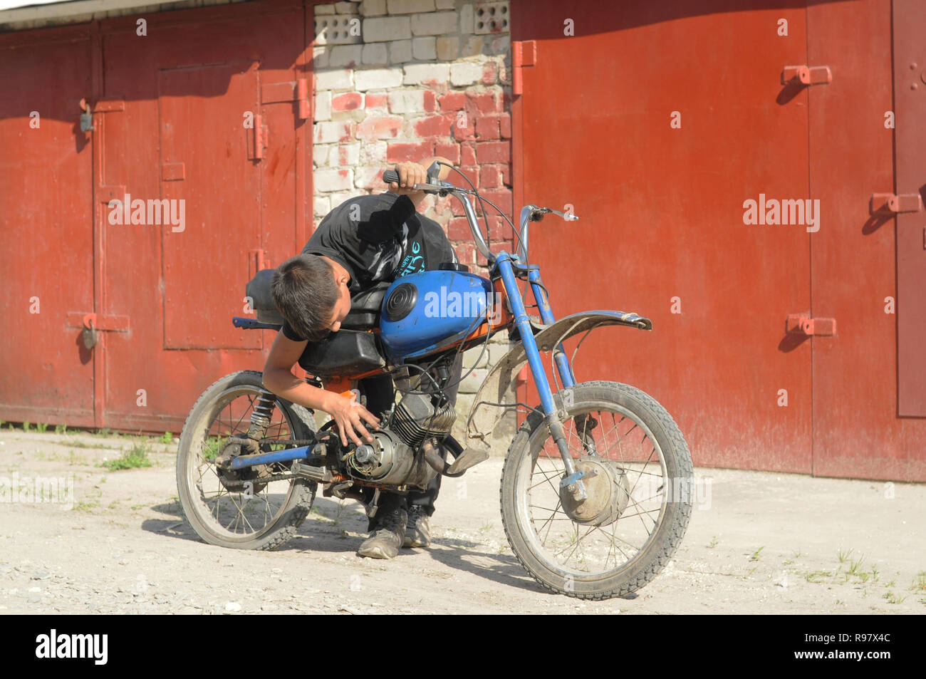 Kovrov, Russia. Il 14 luglio 2013. Teen riparazioni Karpaty ciclomotore nel territorio garage complesso per i proprietari privati di auto e moto al seguito Foto Stock