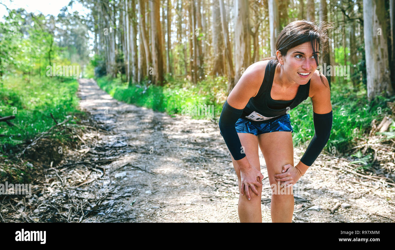 Atleta femminile fermandosi su un sentiero della concorrenza Foto Stock