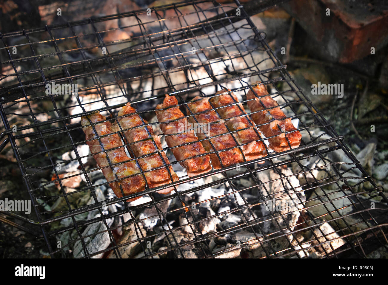 Grigliare salsicce becon avvolto sul grill Foto Stock