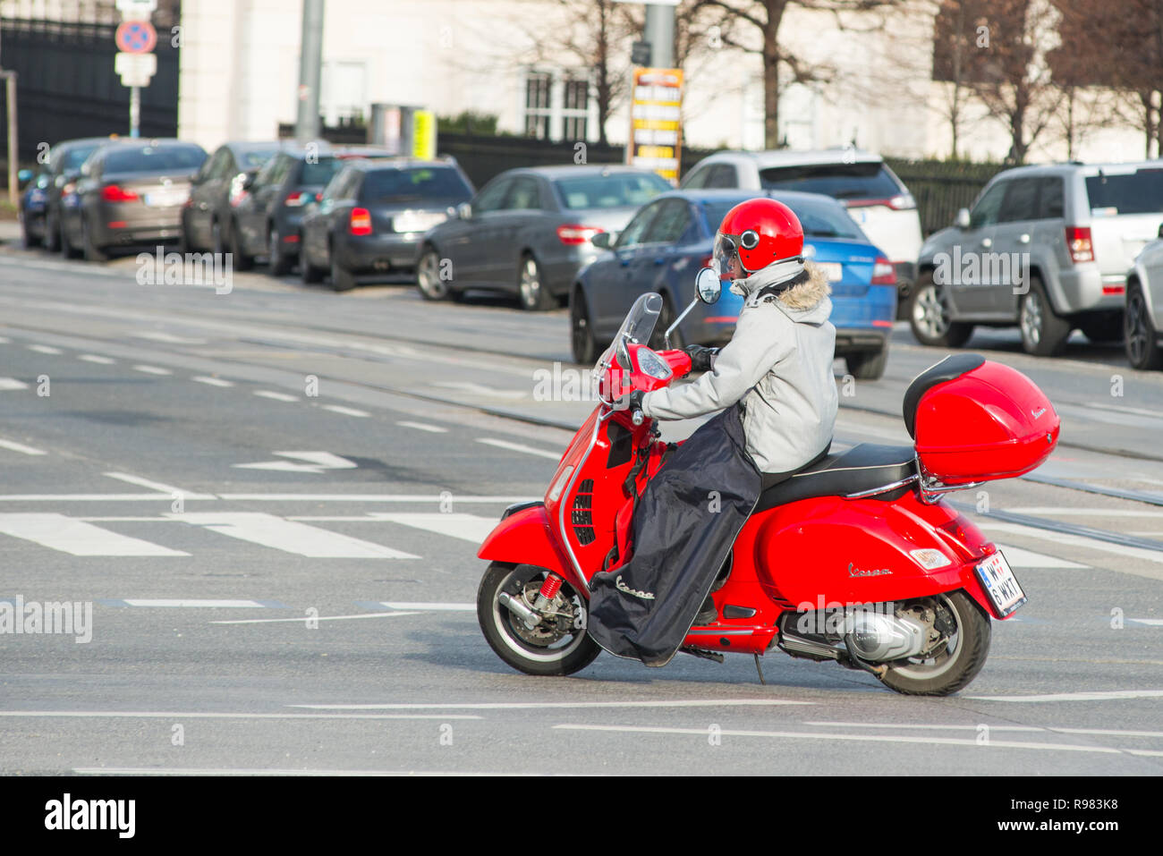 Ragazza di un rosso scooter Vespa con abbinamento di casco per le strade di Vienna, Austria. Foto Stock
