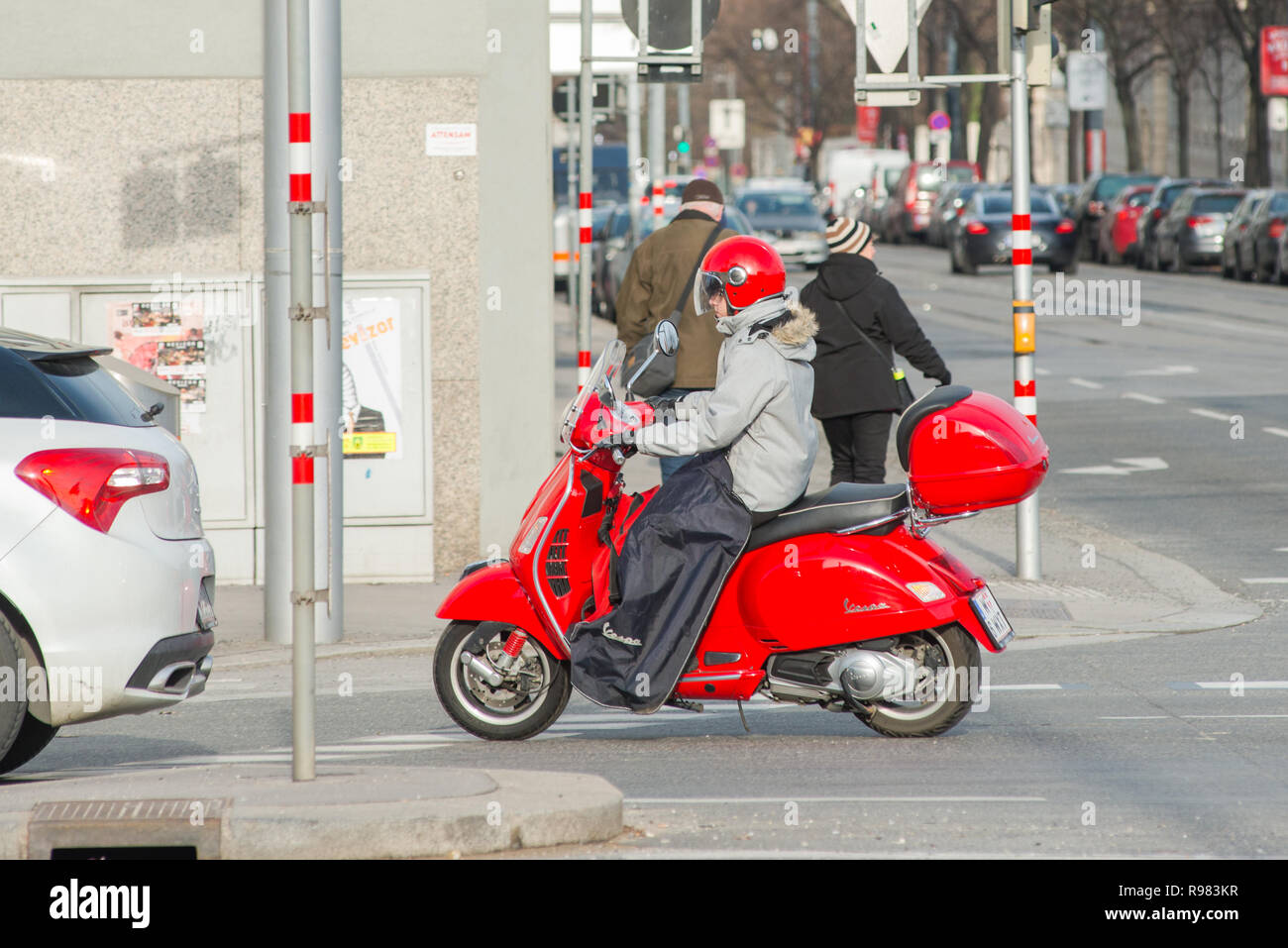 Ragazza di un rosso scooter Vespa con abbinamento di casco per le strade di Vienna, Austria. Foto Stock