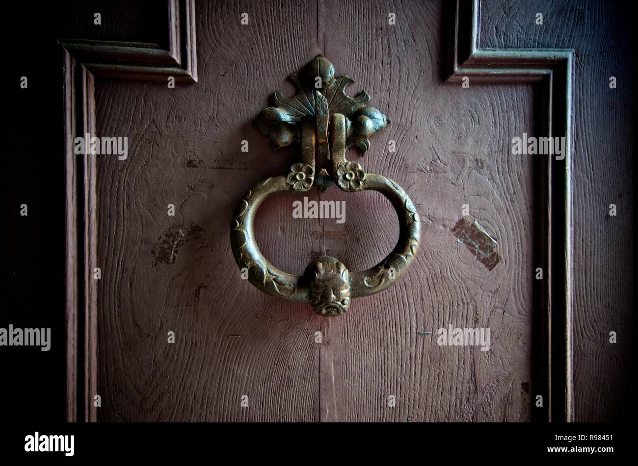 Close up di un ferro battuto respingente scolpito su un marrone porta di legno. Francia Foto Stock