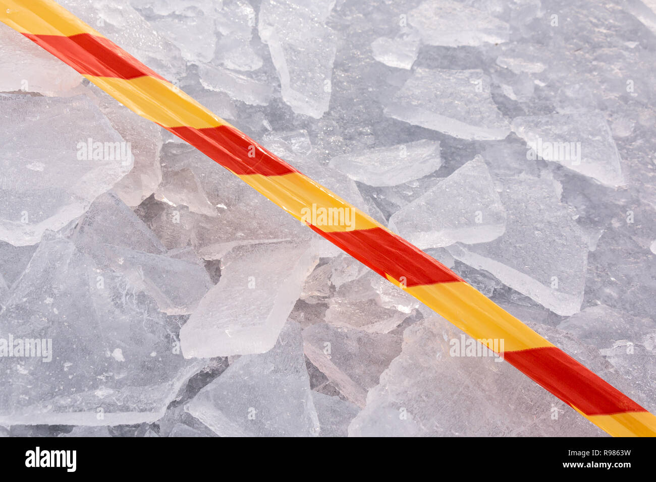 Rosso e giallo di avvertimento su nastro pezzi rotti di ghiaccio su ghiaccio di un lago ghiacciato. Foto Stock