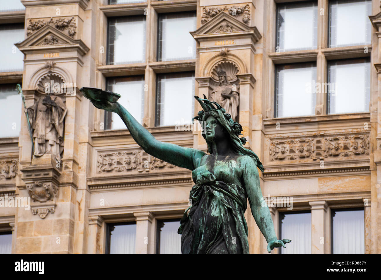 Dettaglio della statua di ornati di donna nella fontana con antico edificio in background Foto Stock