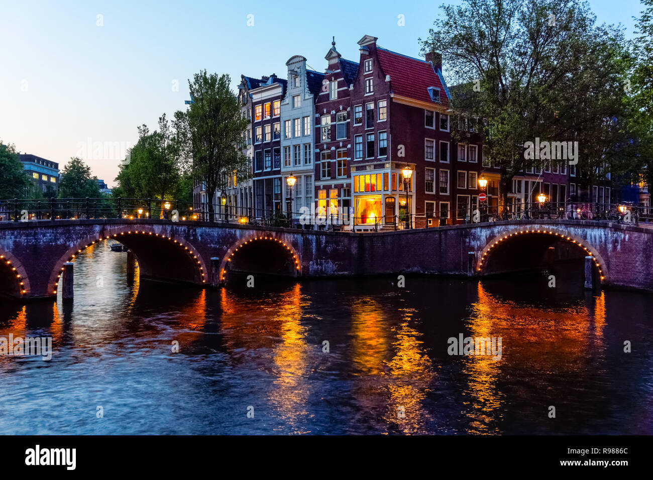 Tradizionali case a schiera olandesi e ponti illuminati sul canale Keizersgracht ad Amsterdam, Paesi Bassi, Europa Foto Stock