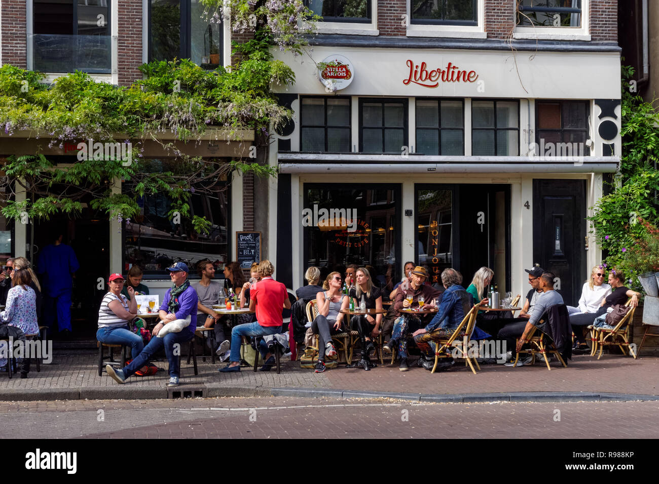 I giovani seduti e bere fuori Libertine Cafe a Amsterdam, Paesi Bassi Foto Stock