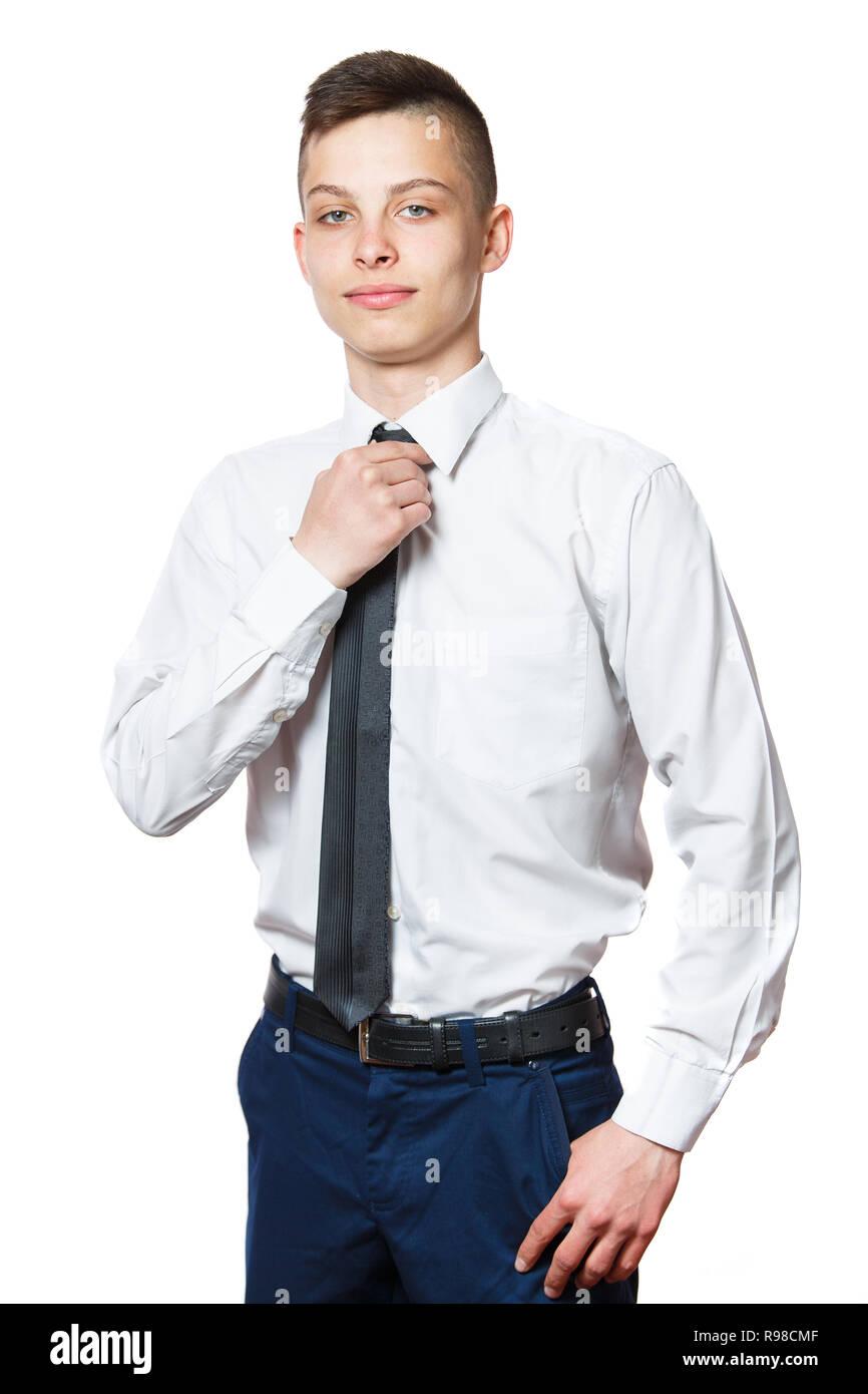 Fiducioso grave ragazzo adolescente con le sue mani in blue jeans tasche che indossa una camicia bianca e indebolire la cravatta. Isolato su sfondo bianco, maschera inclusa. Foto Stock