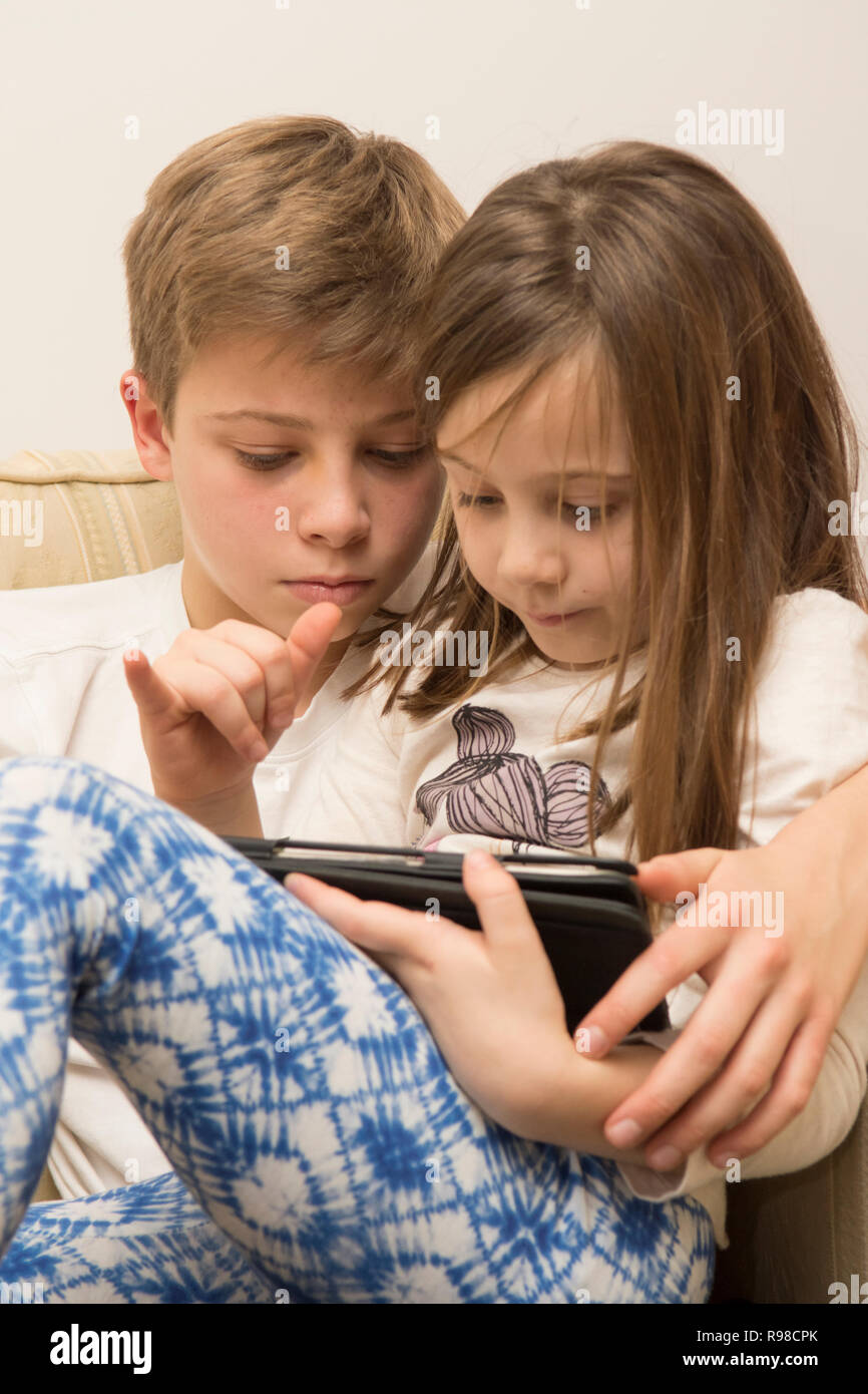 Dispositivo digitale, tablet, iPad fratello aiutando sorella più giovane con i social media, tecnologia moderna Foto Stock