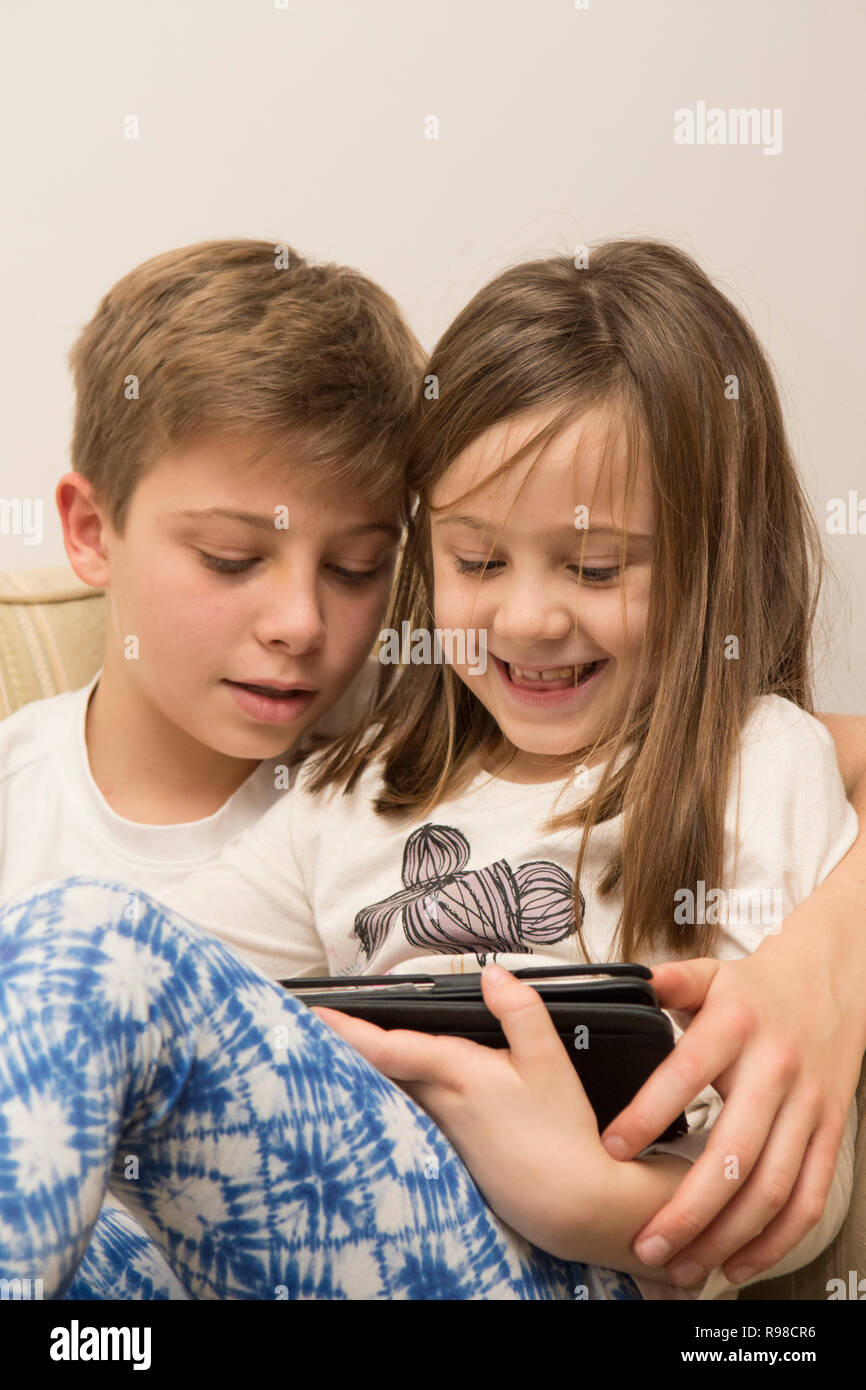 Dispositivo digitale, tablet, iPad fratello con la sorella più giovane giochi sul dispositivo elettronico. Foto Stock