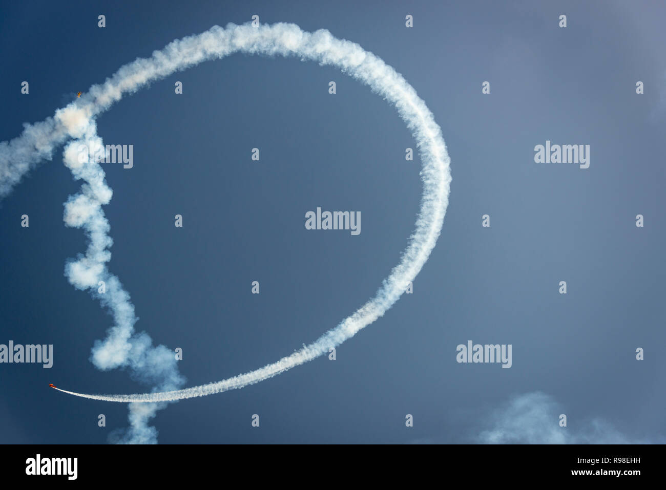 La forma della lettera d lasciato dai sentieri di fumo di un velivolo acrobatico contro un cielo blu Foto Stock
