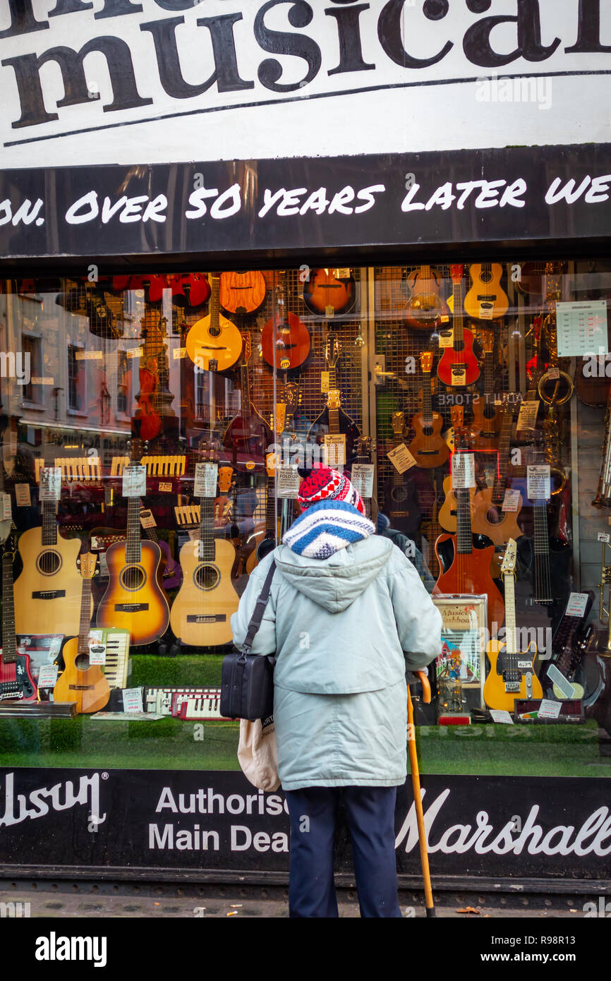 Vecchia Signora Cerca nello store negozio di fronte del famoso Macaris Strumenti Musicali shop in Charing Cross Road, Londra Foto Stock