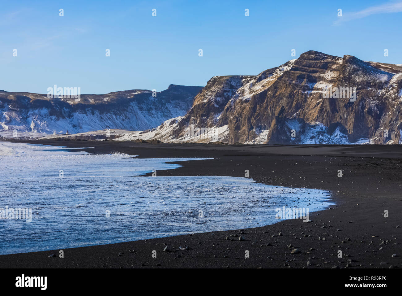 Potenti onde che si infrangono lungo la spiaggia di Reynisfjara, una spiaggia di sabbia nera nei pressi del villaggio di Vik, in inverno in Islanda Foto Stock