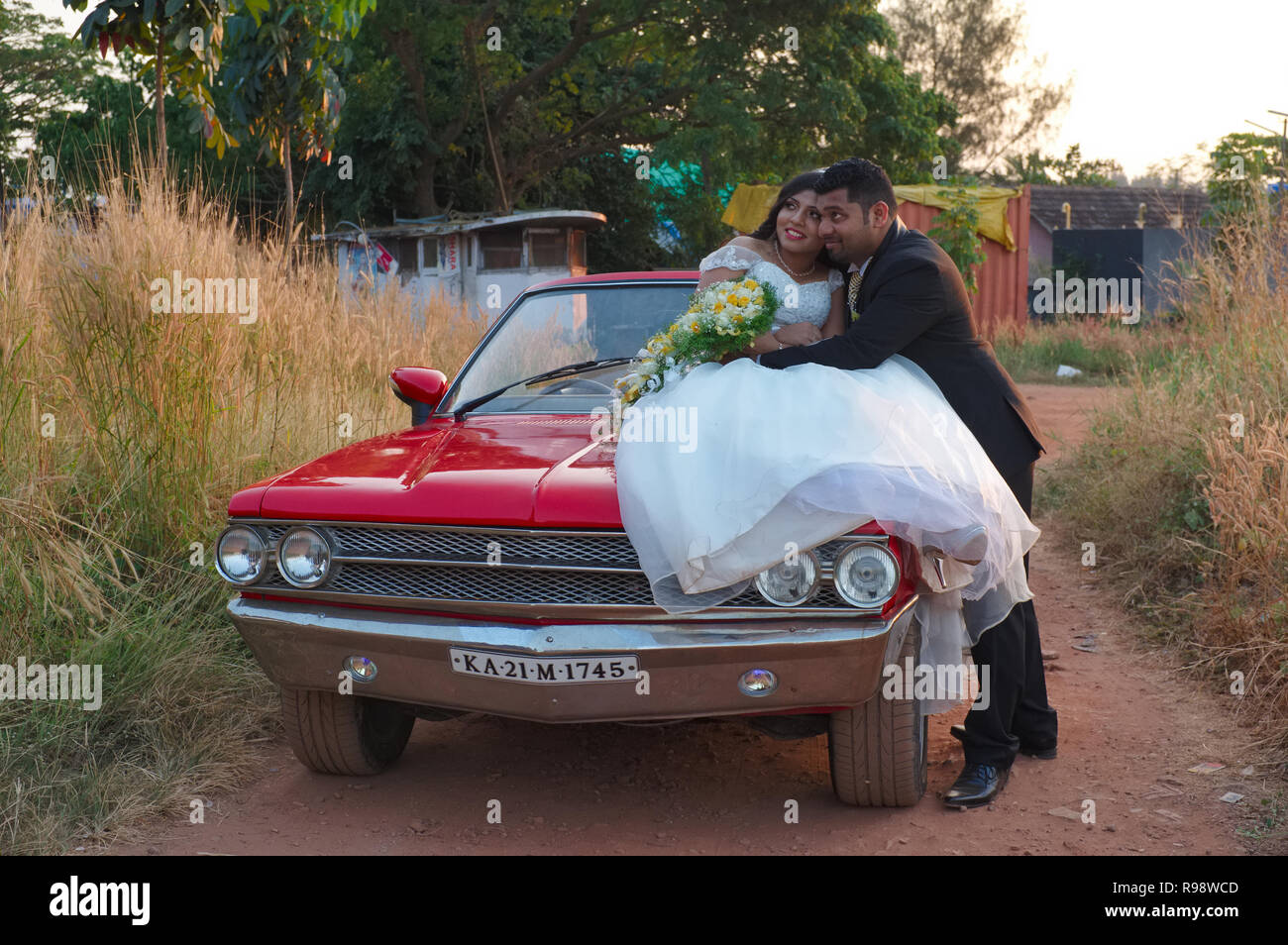 Un sposi Christian paio di Mangalore, Karnataka, India, creando intorno a un'auto d'epoca per le fotografie del vostro matrimonio Foto Stock