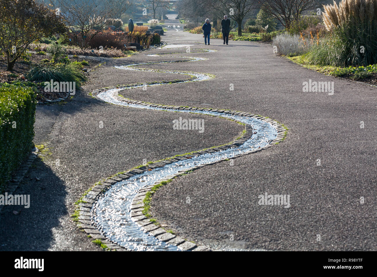 Coppia di mezza età visitare il National Botanic Garden of Wales fate una passeggiata attraverso il giardino a fianco di un flusso Foto Stock