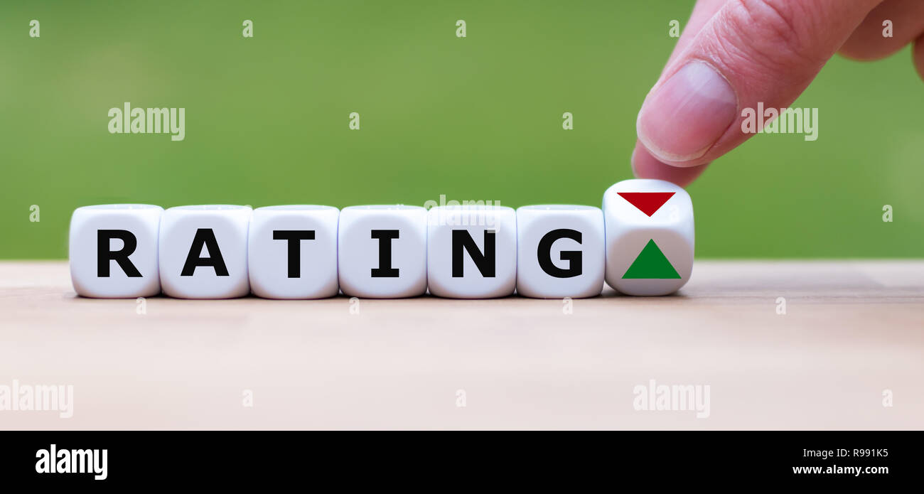 È a mano ruotando un dado e cambia la direzione di una freccia che simboleggia che la valutazione è positiva (o viceversa) Foto Stock