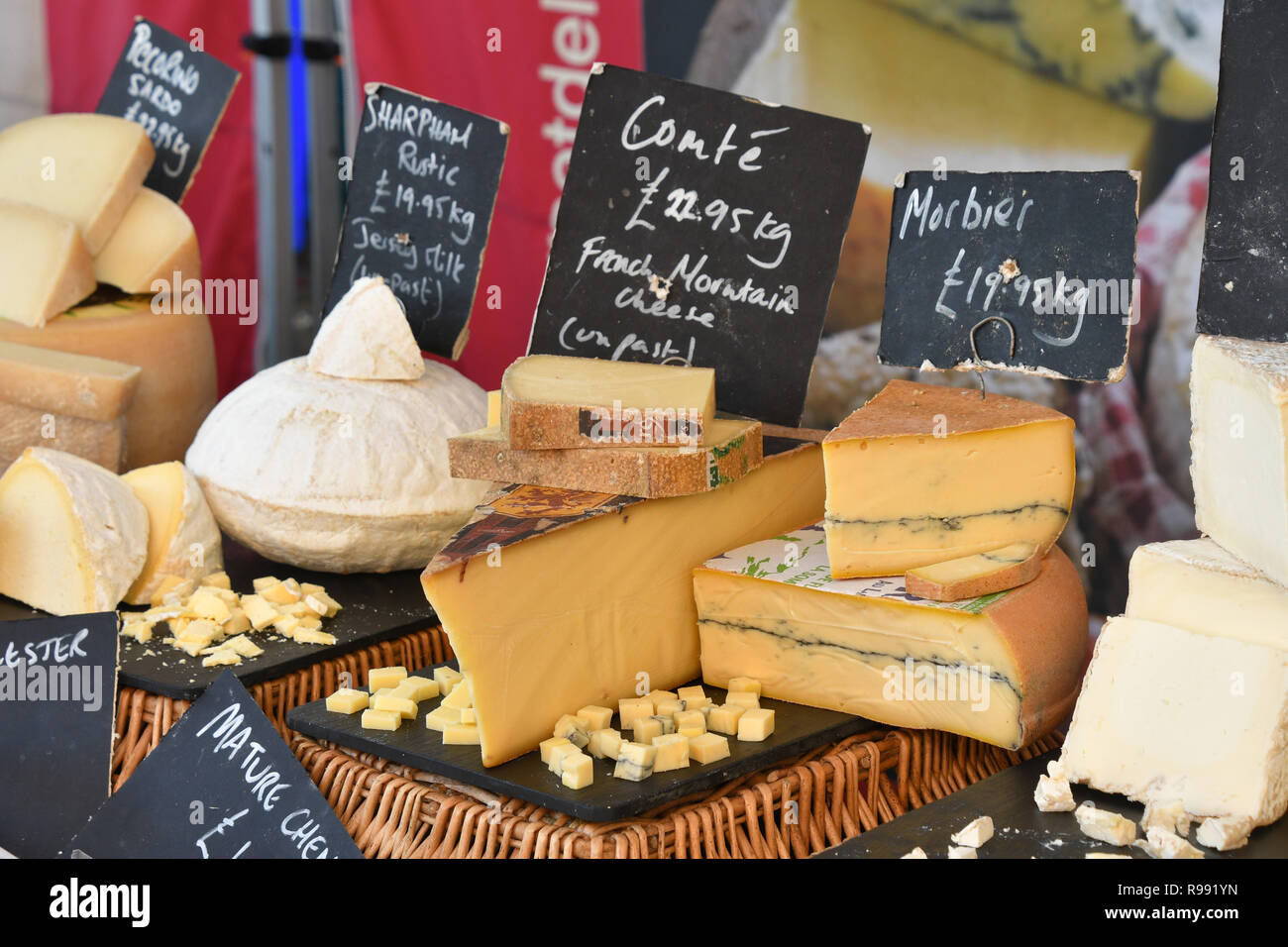 Formaggi sul mercato in stallo Somerset visualizzati con i campioni per la degustazione.Sharpham rustico,Conte francese di formaggio di montagna, Morbier,l'Inghilterra, Regno Unito Foto Stock
