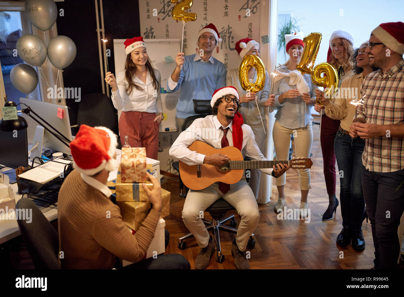 Sorridente team Aziende hanno divertimento e balli in Santa hat a Xmas Party in ufficio Foto Stock