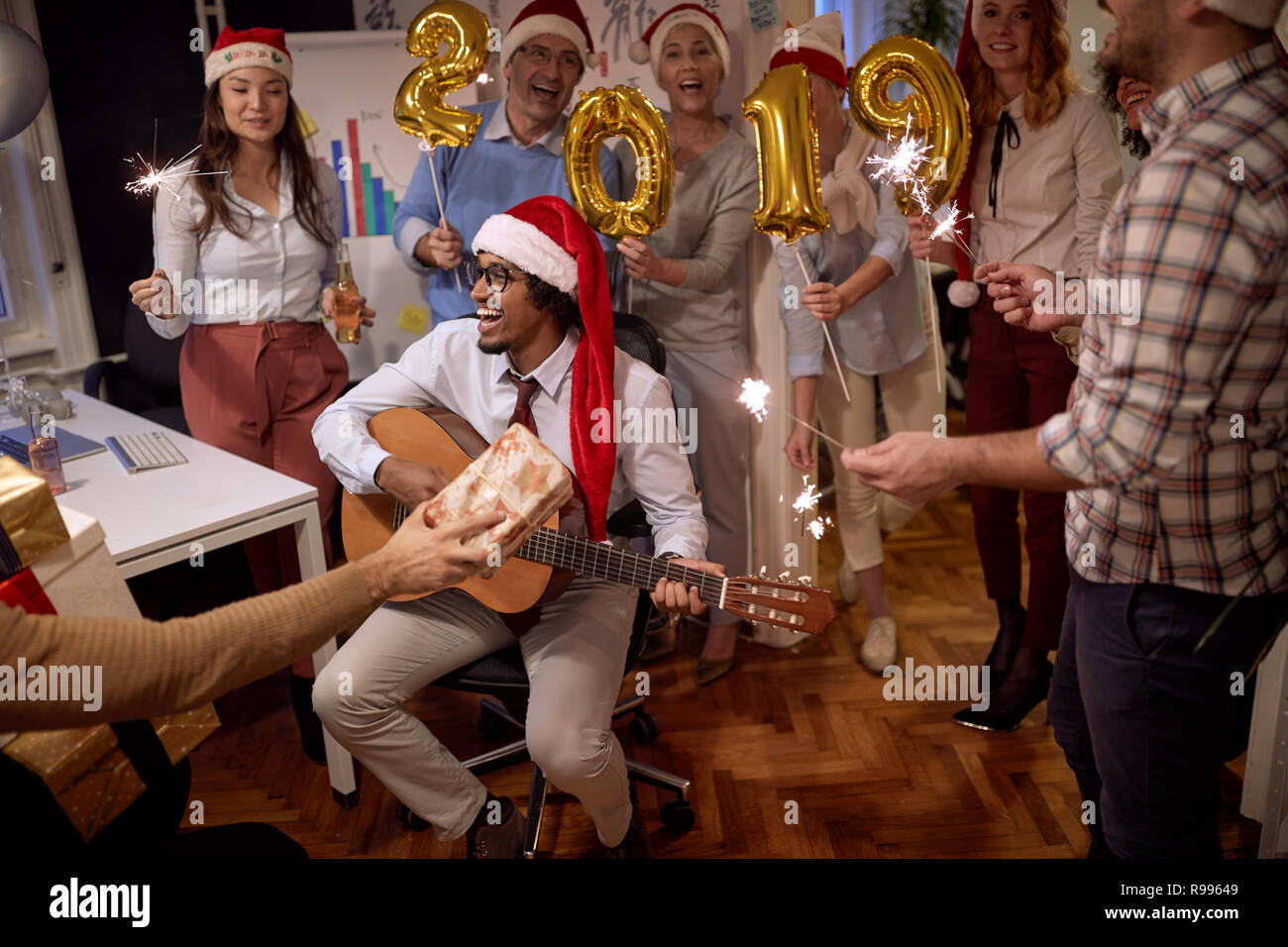 Business di successo di gruppo di persone in Santa hat a Xmas Party in office celebrando con la canzone Foto Stock