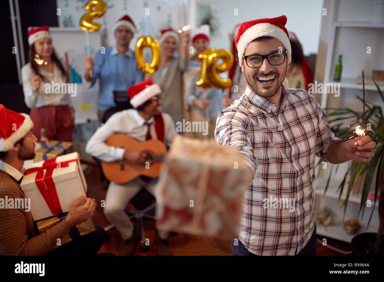 Happy business man divertirsi in Santa hat e scambio di doni a Xmas Party con i suoi colleghi in ufficio Foto Stock