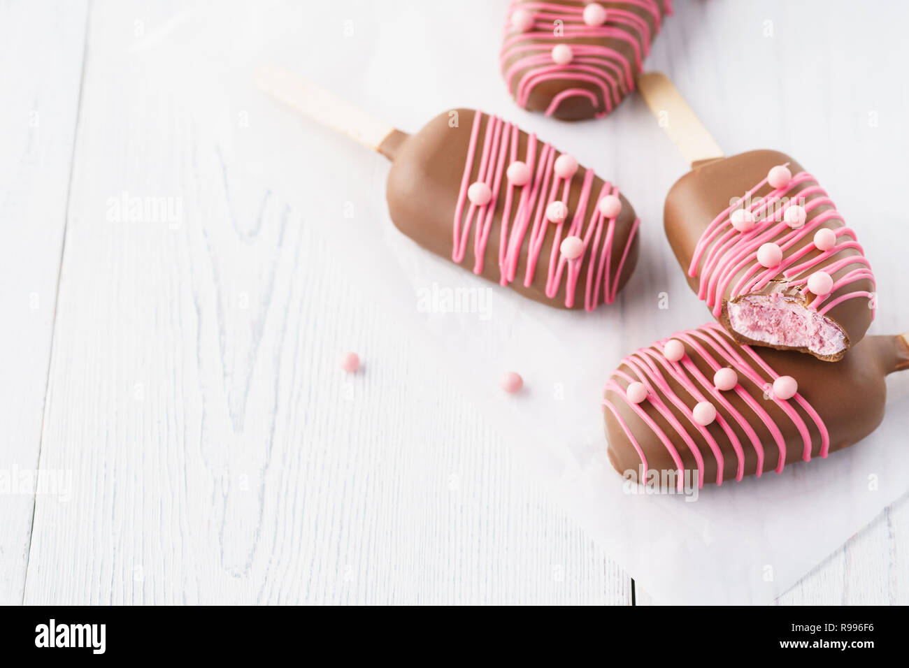 Il cioccolato immerso marshmallow a forma di gelati su un bastone. Foto Stock