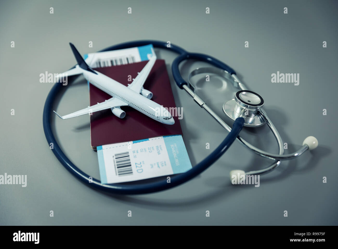 Assicurazione di viaggio - passaporto con biglietto di volo e uno stetoscopio su sfondo grigio Foto Stock