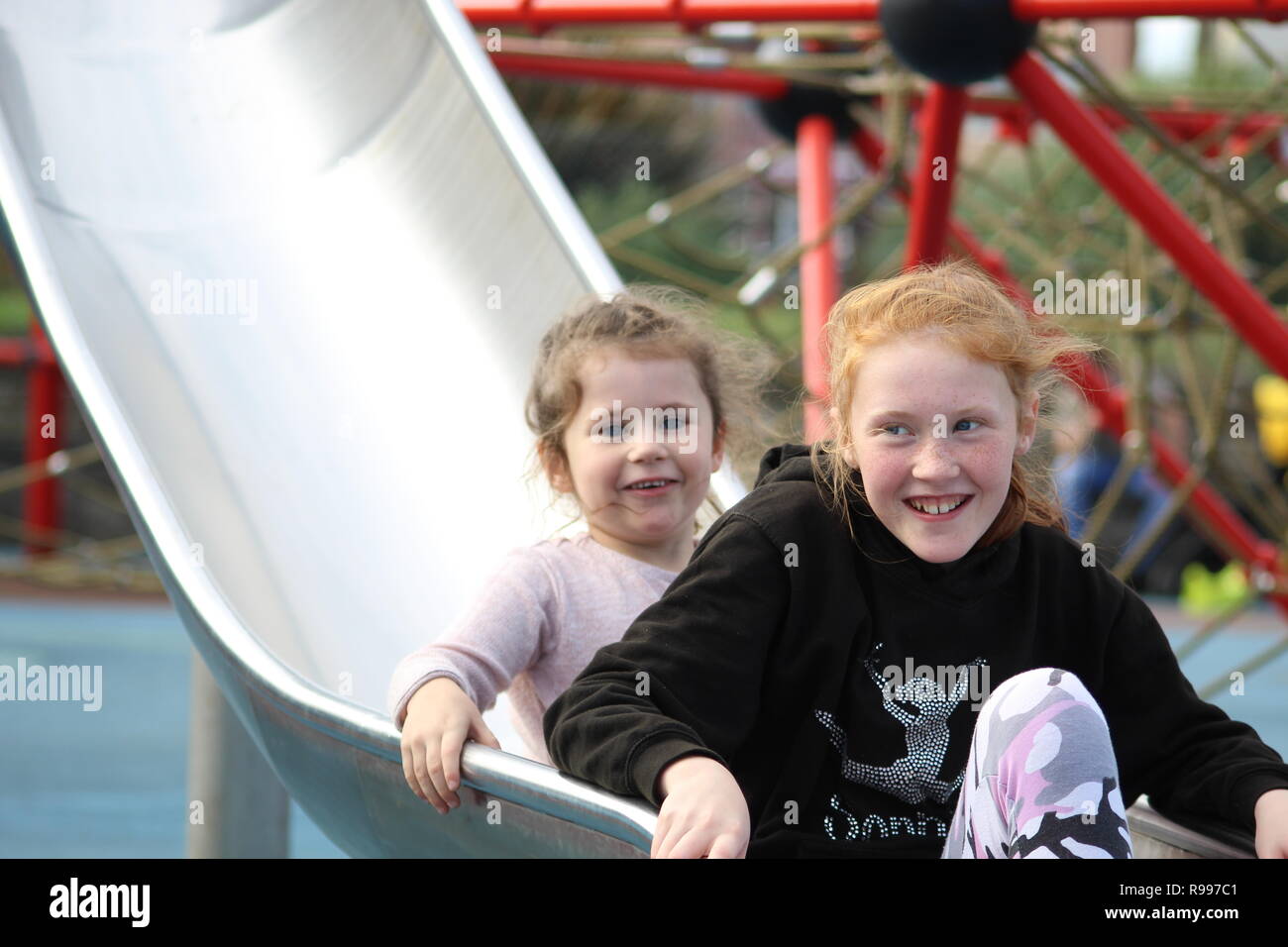 due sorelle scivolano giù per uno scivolo nel parco di skegness (parco del sole) Foto Stock