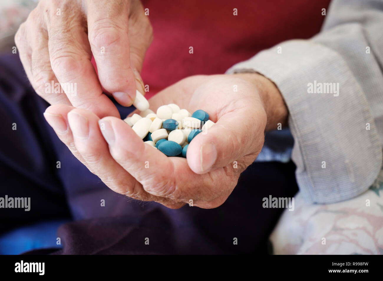 Primo piano di un anziano uomo caucasico con un mucchio di diverse pillole in mano Foto Stock