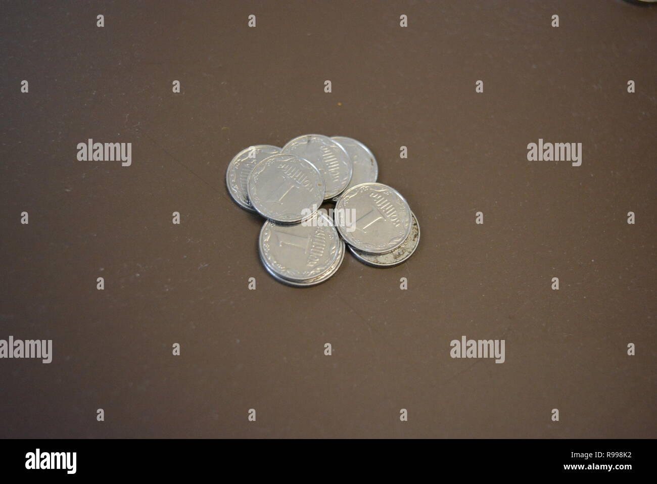 Moneta di metallo su fondo marrone, hrivnia Ucraina e un penny, pagamento in banca, pagamento di tesori e contanti, risparmi in banca. Foto Stock