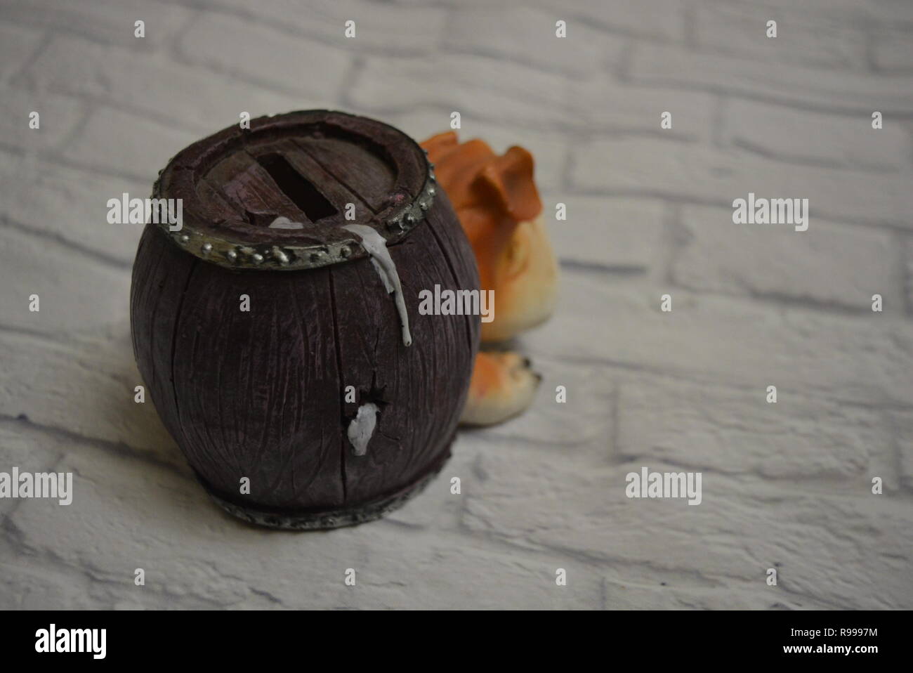 Vassoio antigoccia in ceramica sotto forma di botte di birra con testa di cane e un bicchiere di birra blu accanto sullo sfondo di una parete di mattoni bianchi. Foto Stock